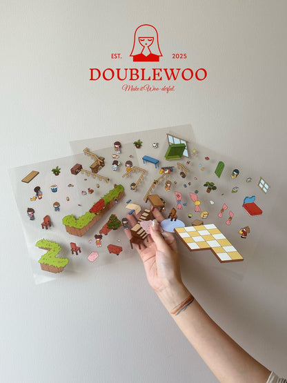 Clear PET sticker sheets showing vibrant characters, party props, green hedges, and casual living room furniture, held by hand for scale and clarity.