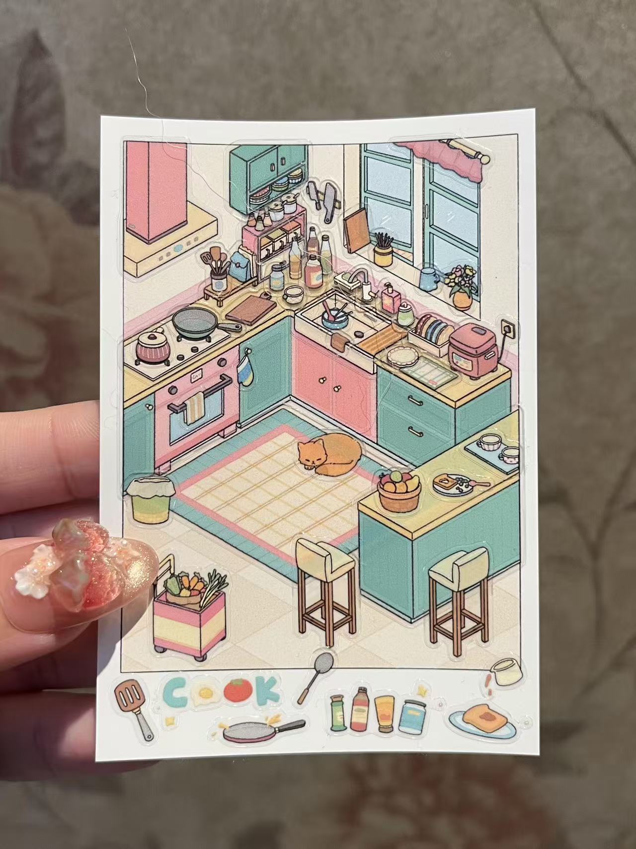 Illustration of a colorful kitchen with various appliances and furniture, held by a hand.