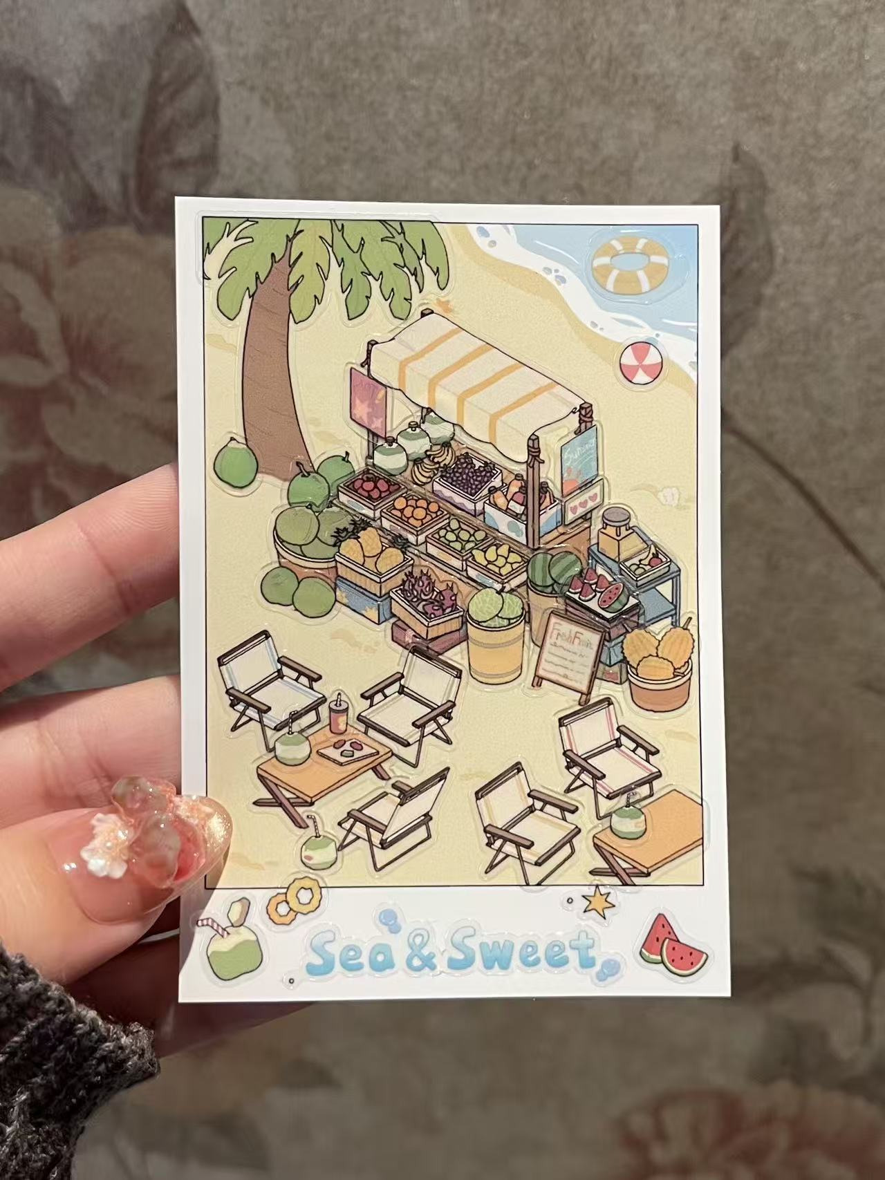Illustrated card of a beachside food stand with chairs and tables, held by a hand.