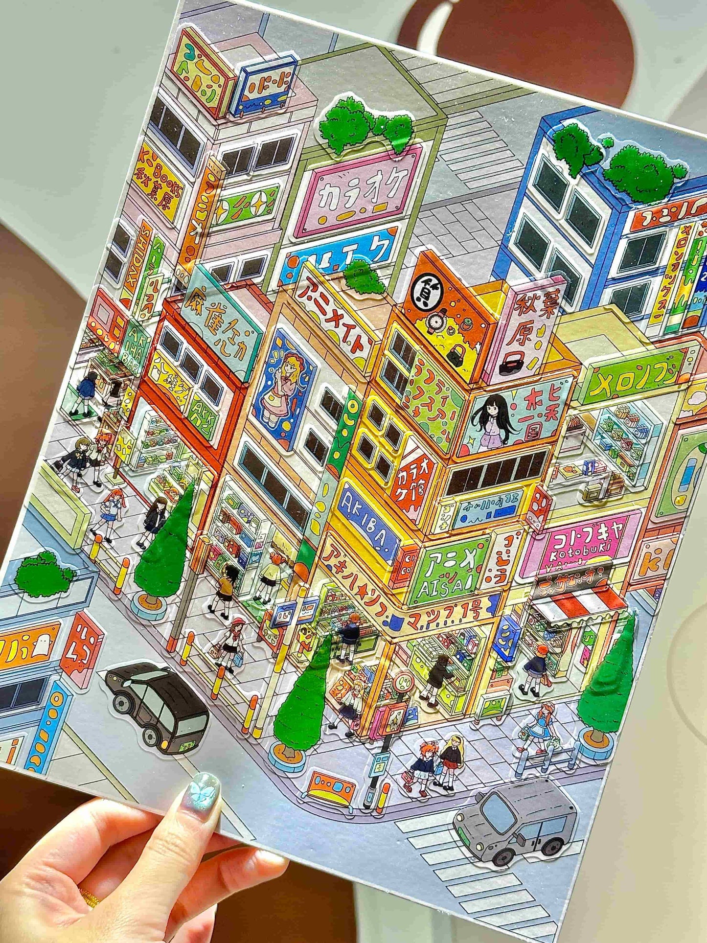 Colorful illustration of a city street scene on a paper, held by a hand.